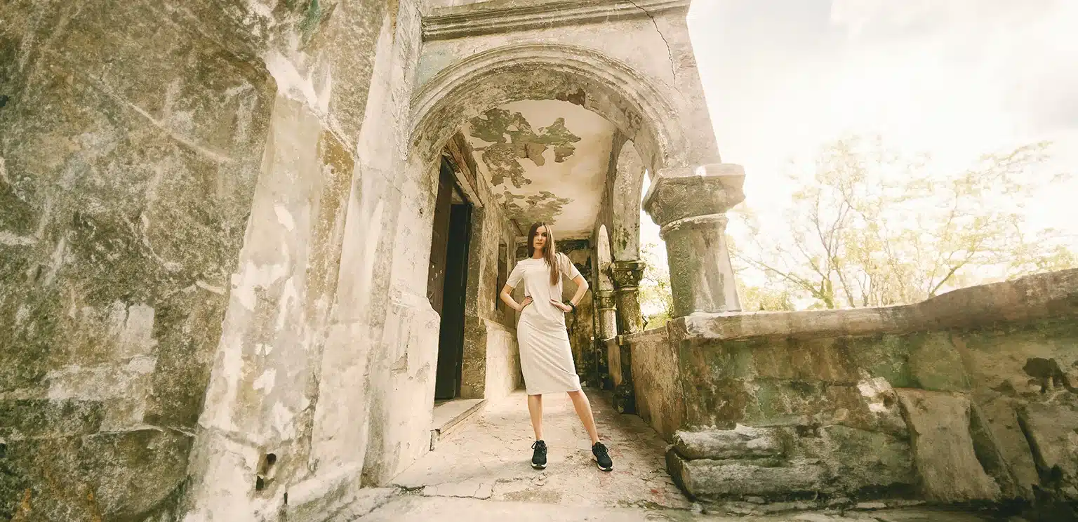stylish girl posing in an old venetian lodge in corfu built of stone